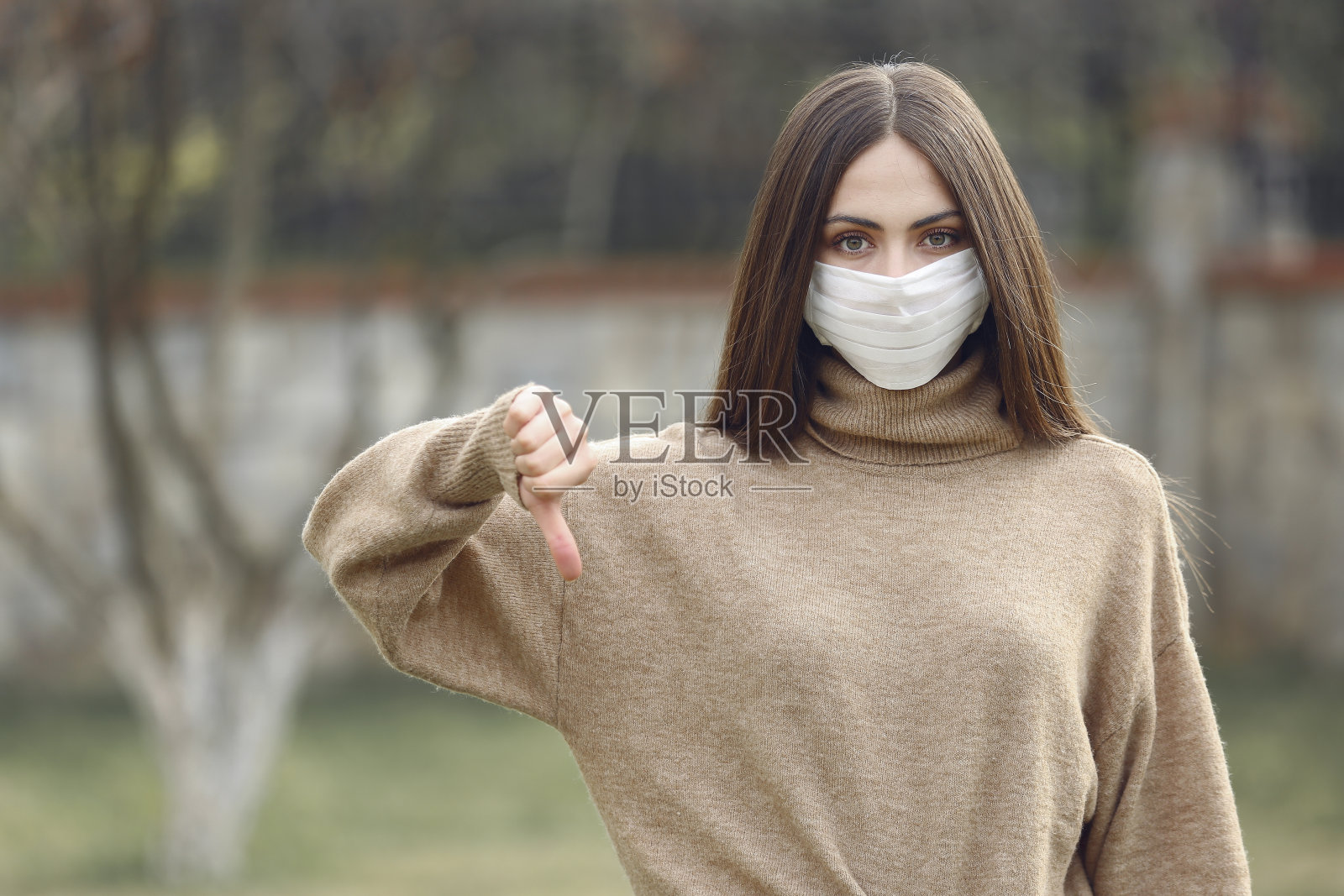 学生戴着面具，做拇指向下的手势照片摄影图片