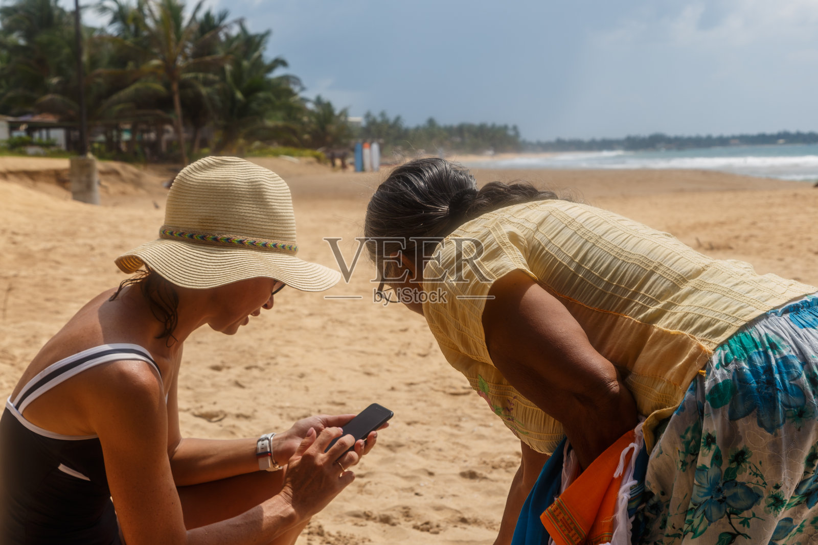 在斯里兰卡，欧洲女性向当地商人展示手机上的价格照片摄影图片