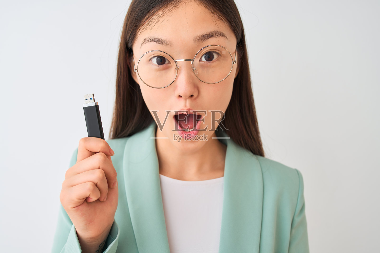 年轻的中国女商人手持usb存储器，在孤立的白色背景下惊恐地面对着震惊、害怕和兴奋的恐惧表情照片摄影图片