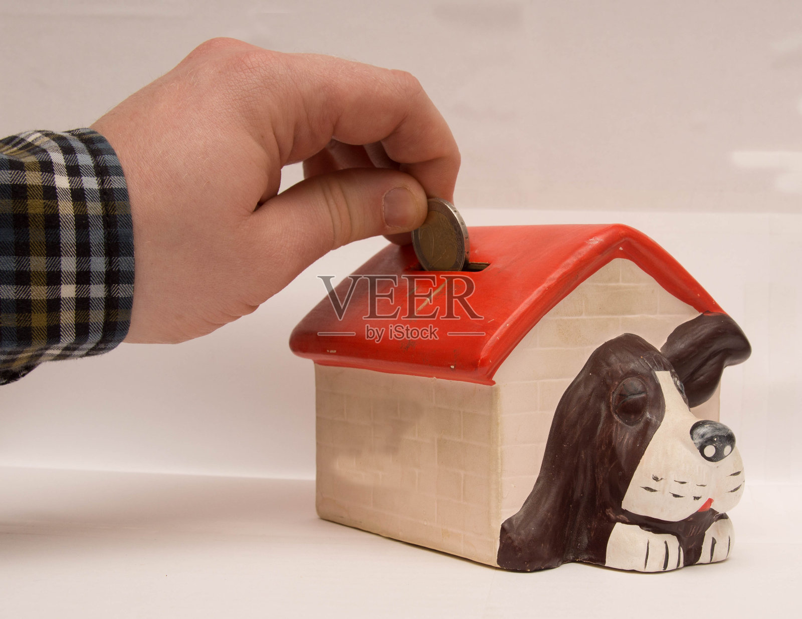 男人把硬币投进储蓄银行照片摄影图片