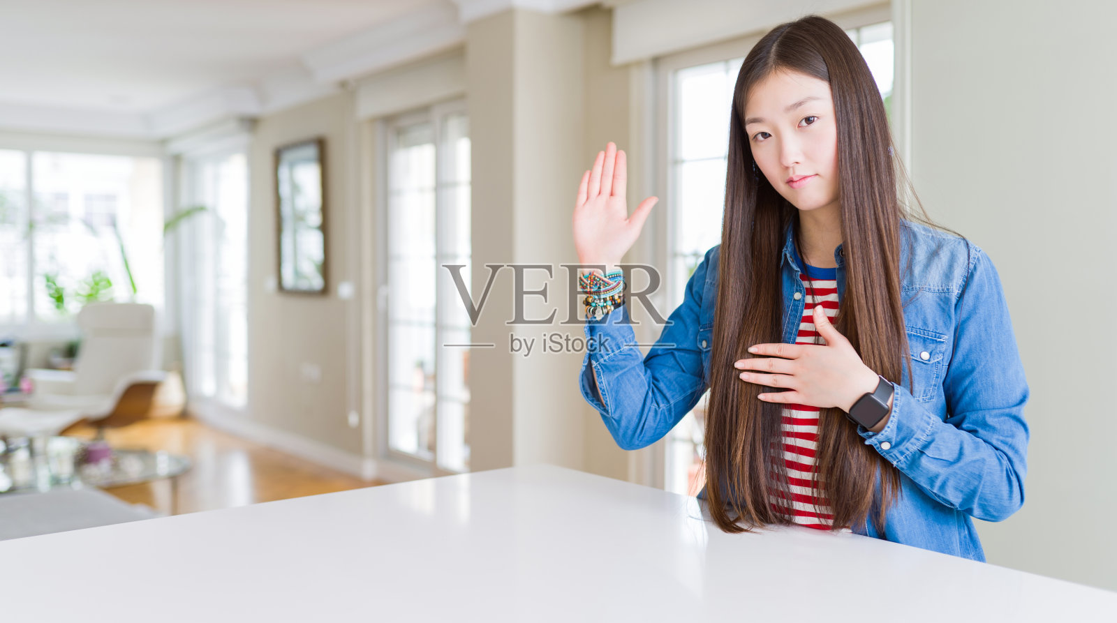 年轻美丽的亚洲女子长头发穿着牛仔夹克发誓与手在胸前和打开的手掌，作出忠诚的承诺誓言照片摄影图片