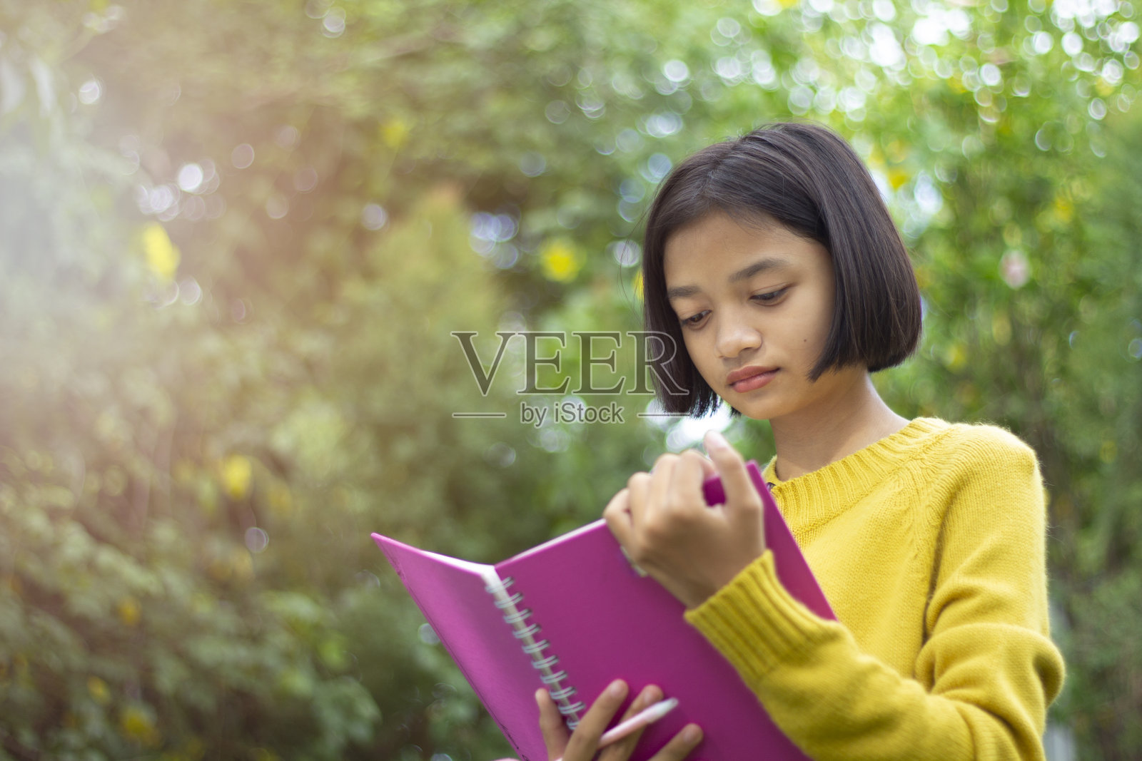 快乐年轻的阿塞恩女孩拿着绿色背景的笔记本。照片摄影图片