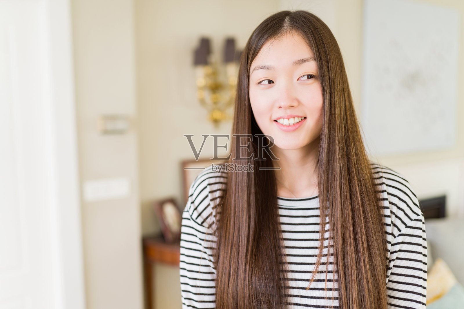 美丽的亚洲女人穿着条纹毛衣在客厅背景微笑看一边和凝视远离思考。照片摄影图片