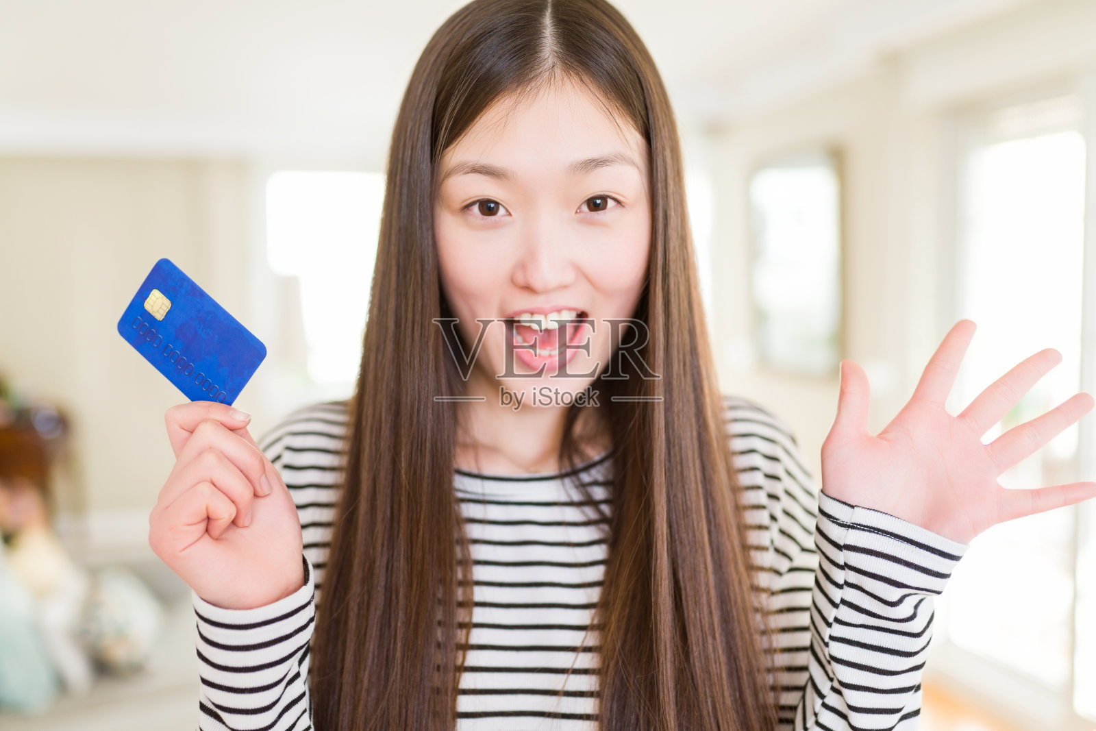 美丽的亚洲女人拿着信用卡非常高兴和兴奋，胜利者的表情庆祝胜利尖叫着大大的微笑和举起手照片摄影图片