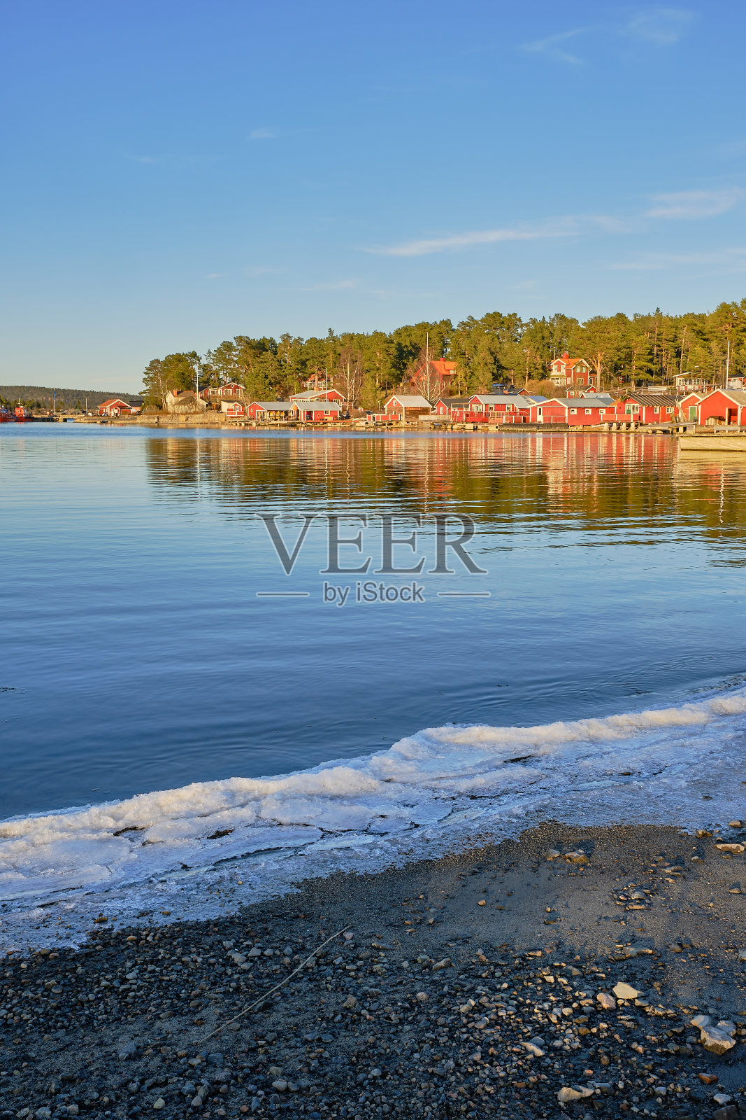 前景是海边结了冰的红色小屋照片摄影图片