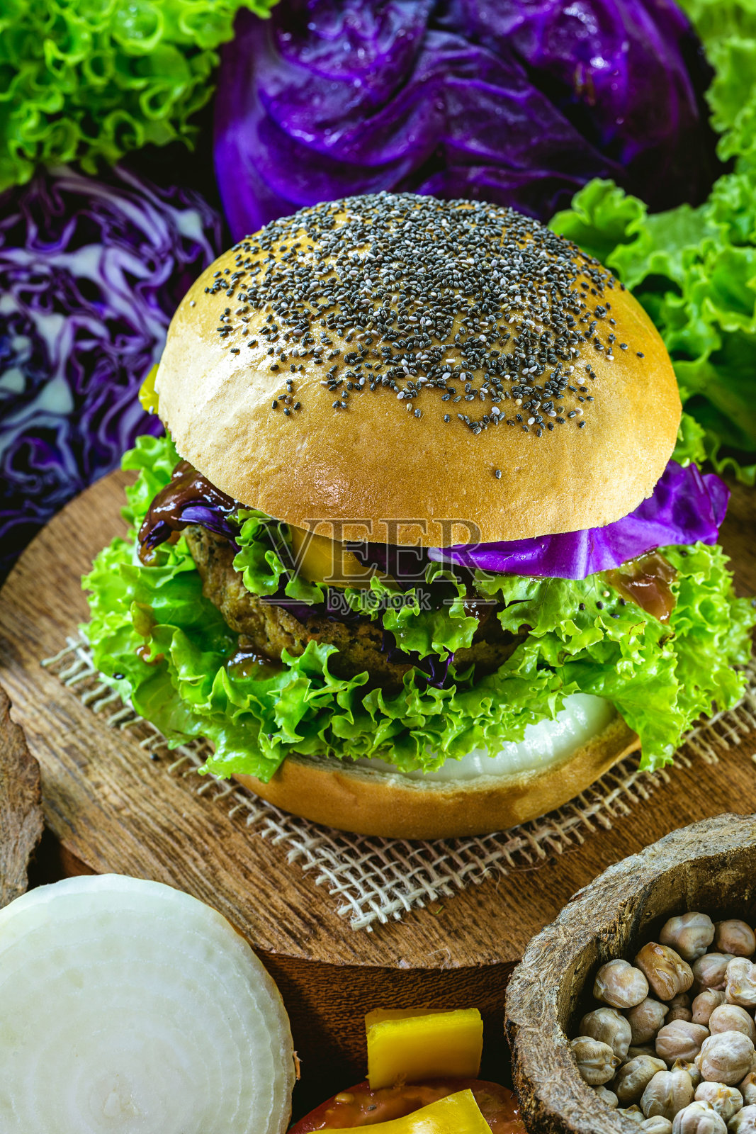 大的烤素食汉堡，由鹰嘴豆和大豆和蛋白质制成。健康素食的生活理念。五颜六色的食物，辣椒，红卷心菜，西红柿，洋葱，鹰嘴豆，大豆，生菜和碱液照片摄影图片