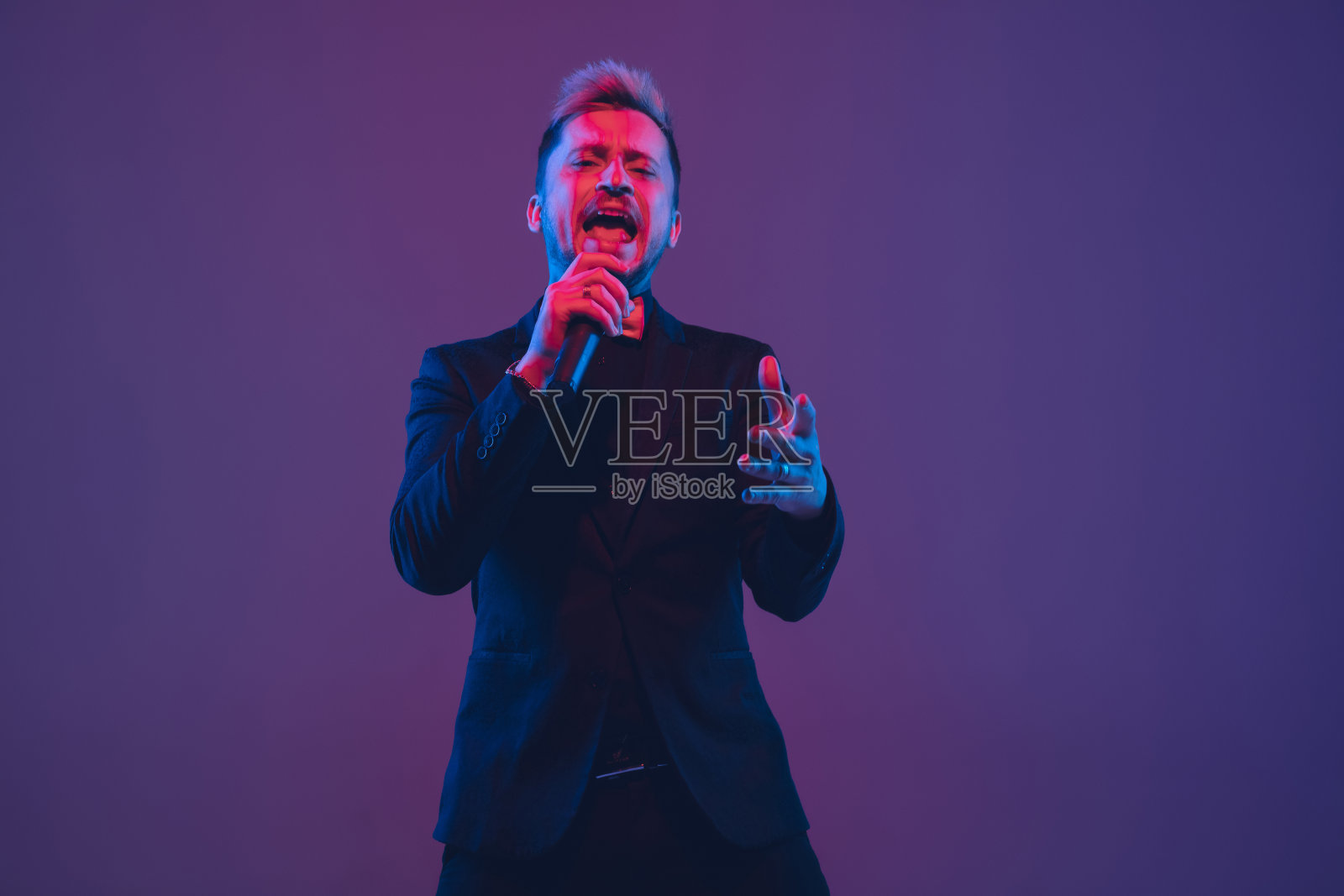 年轻的白人音乐家、表演者在渐变背景的霓虹灯下唱歌跳舞照片摄影图片