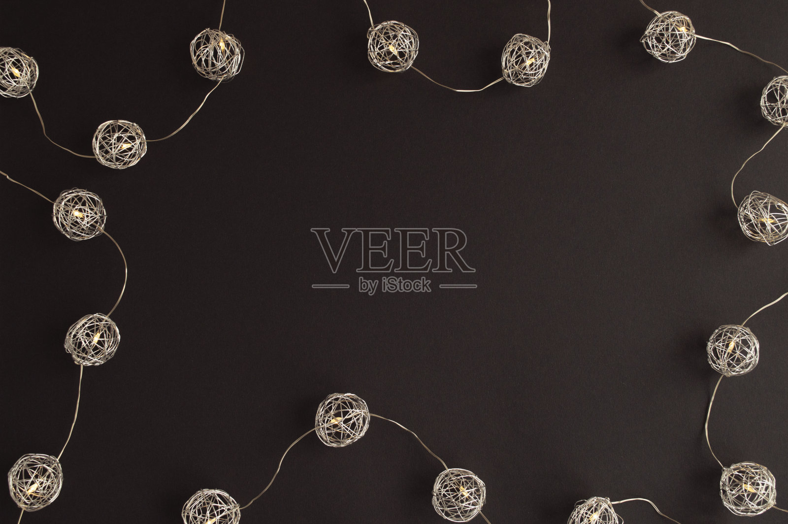 在黑暗的背景上，金属球形灯光环绕文本的空白位置。圣诞节和新年的概念照片摄影图片