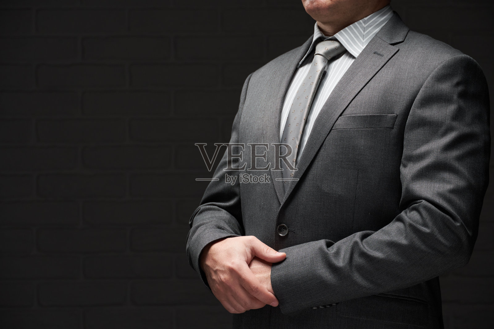 商人肖像穿着灰色西装，深色墙壁背景照片摄影图片