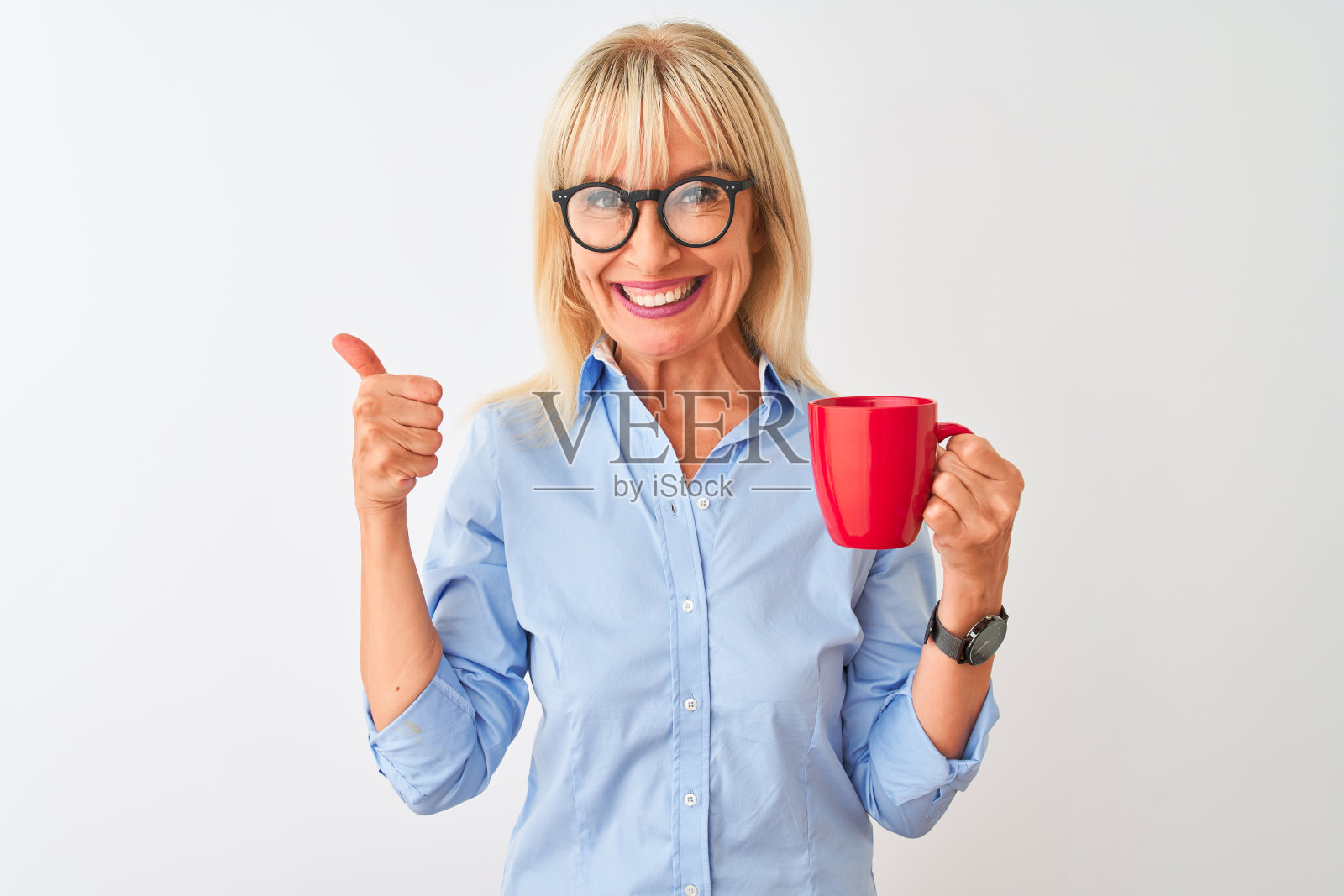 穿着优雅衬衫、戴着眼镜的中年女商人，喝着咖啡，面带微笑，做出OK手势照片摄影图片