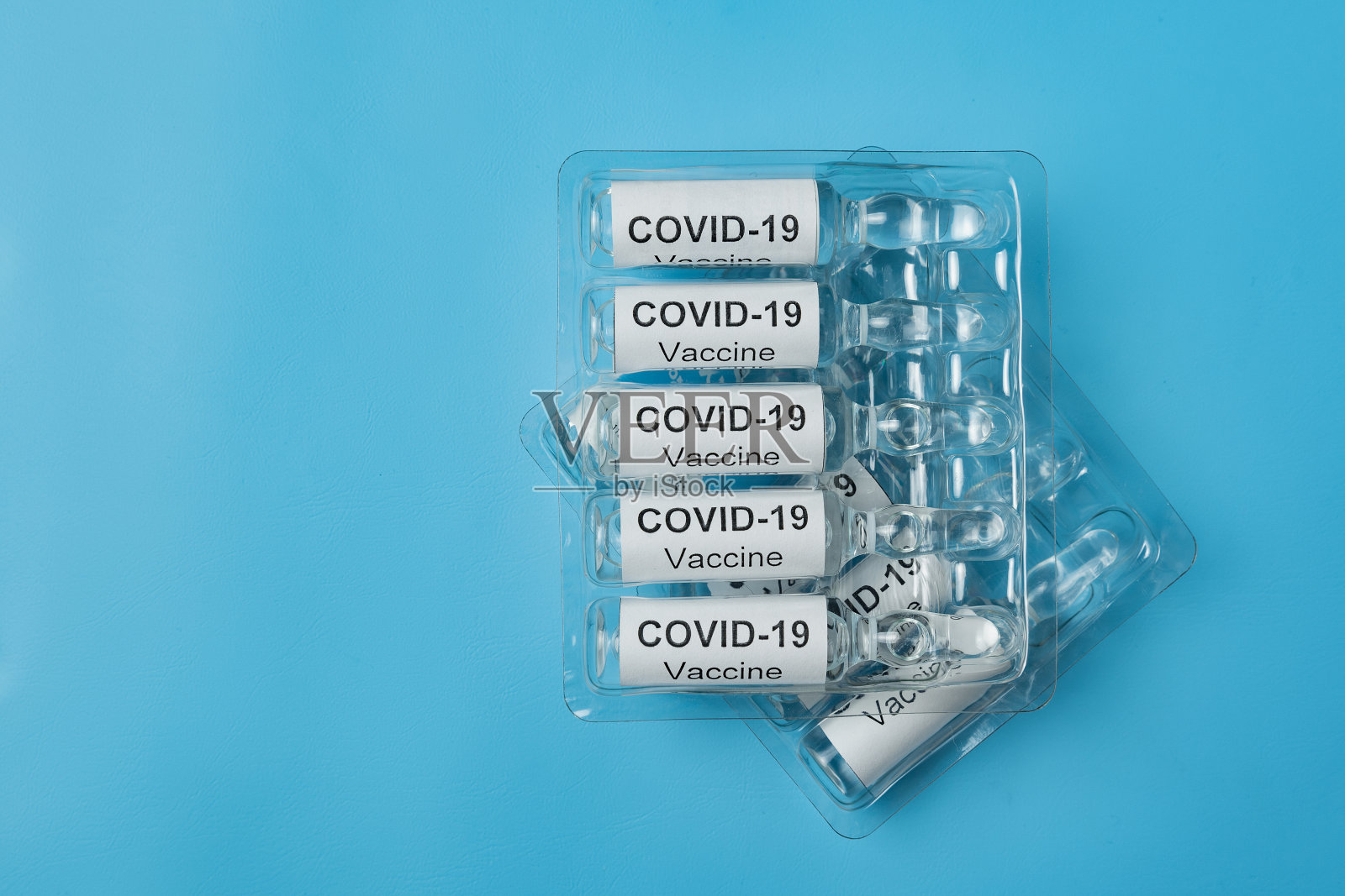 蓝色背景上的新冠疫苗安瓿包装，医学概念照片摄影图片
