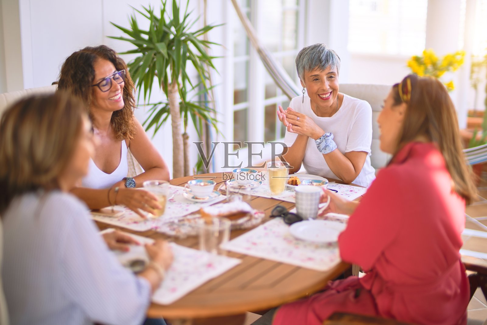 遇见中年妇女吃午饭喝咖啡。阳光灿烂的日子，成熟的朋友在家里开心的微笑照片摄影图片