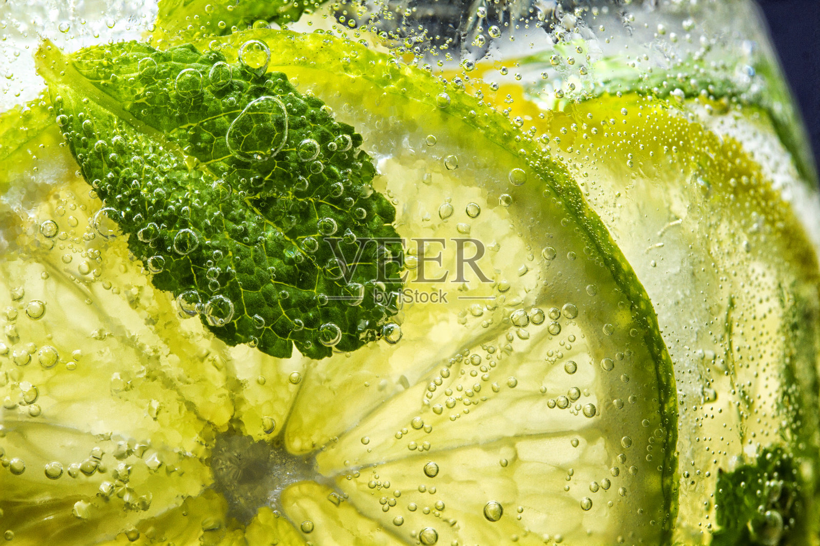 柑橘类的水果。新鲜柠檬和青柠片与薄荷叶在冷水和泡沫。清洁饮食、减肥、健康生活理念。照片摄影图片