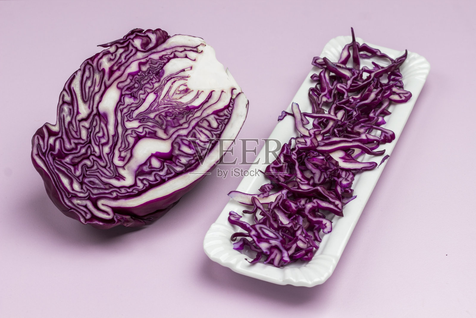 切成两半的红白菜，切成薄片的白菜放在白盘子里。素食食物。照片摄影图片
