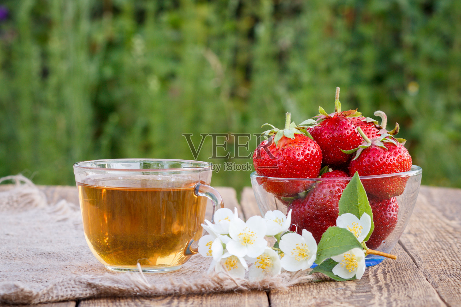 一杯绿茶和红熟草莓在玻璃碗。照片摄影图片