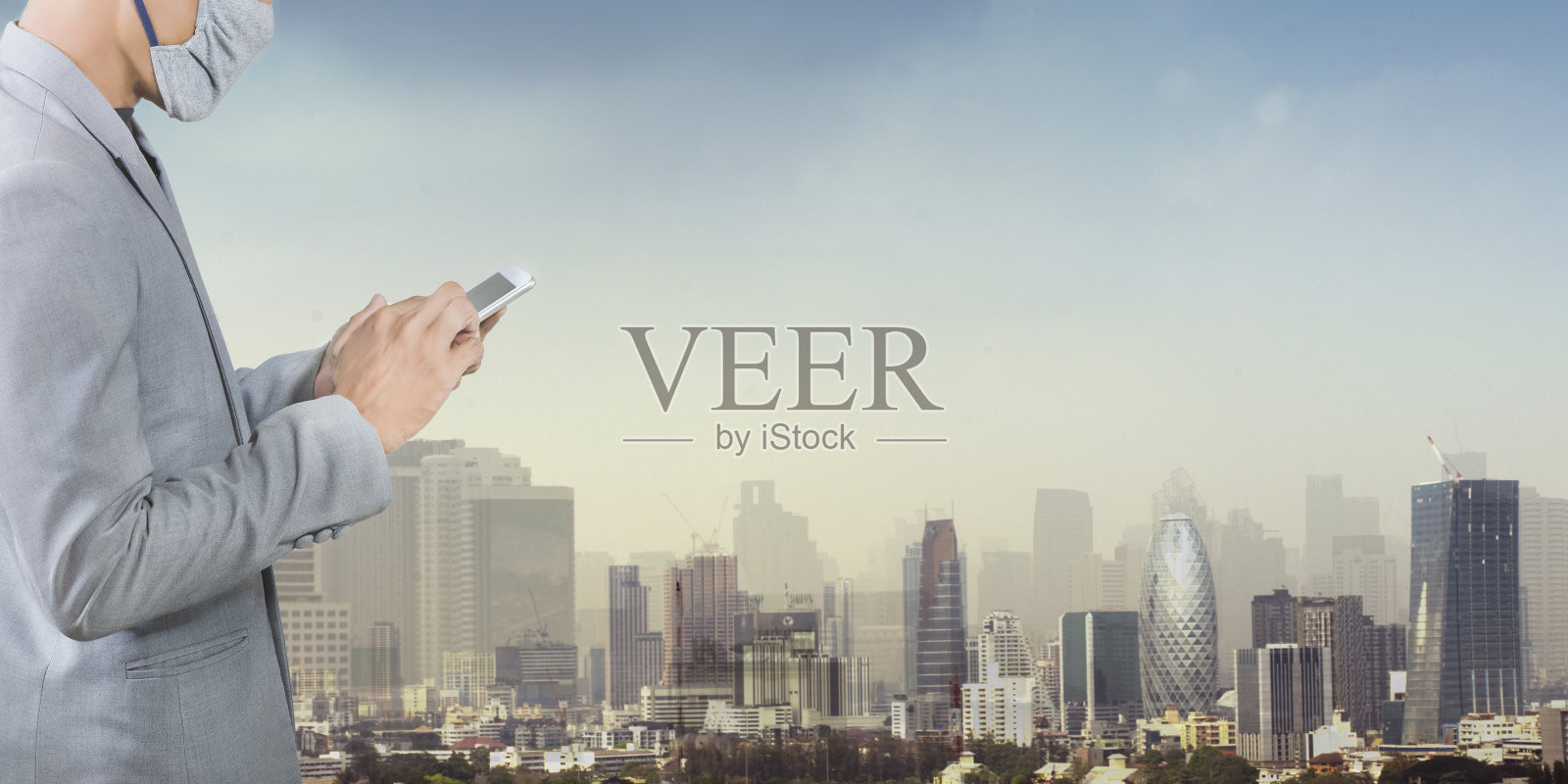 商人戴着面具，孤立在城市背景下。在2020年冠状病毒危机中，提倡人们使用口罩保护自己免受病毒感染。照片摄影图片