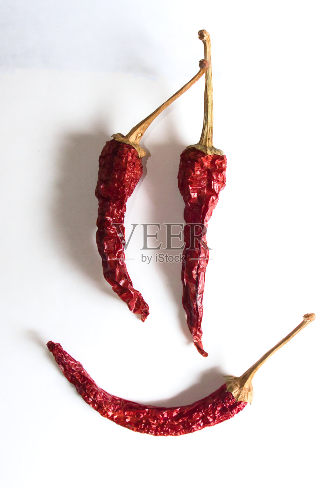 白色背景下红辣椒组成的欢快表情。照片摄影图片