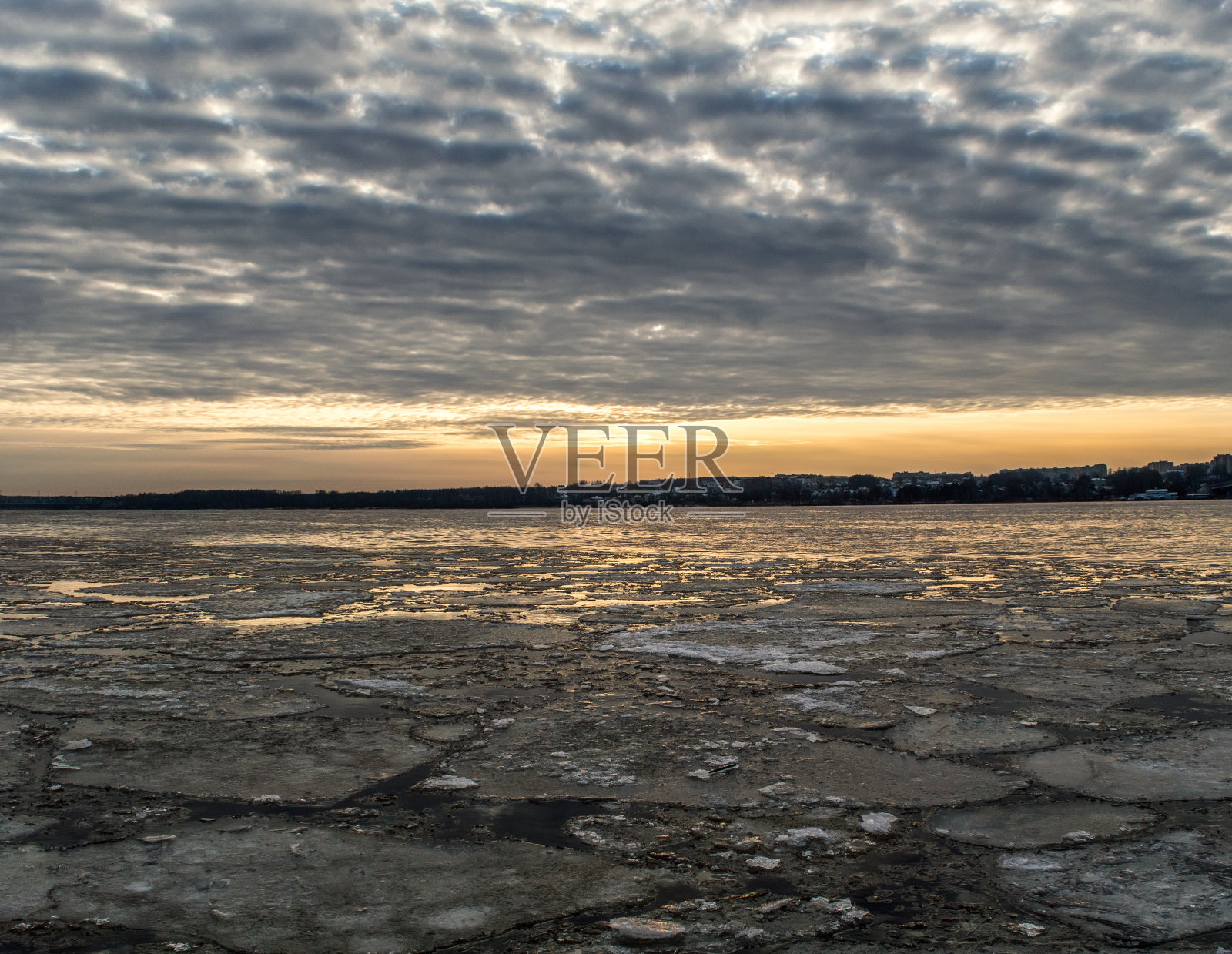 日落时河面上的碎冰。太阳反射。美丽的云。照片摄影图片