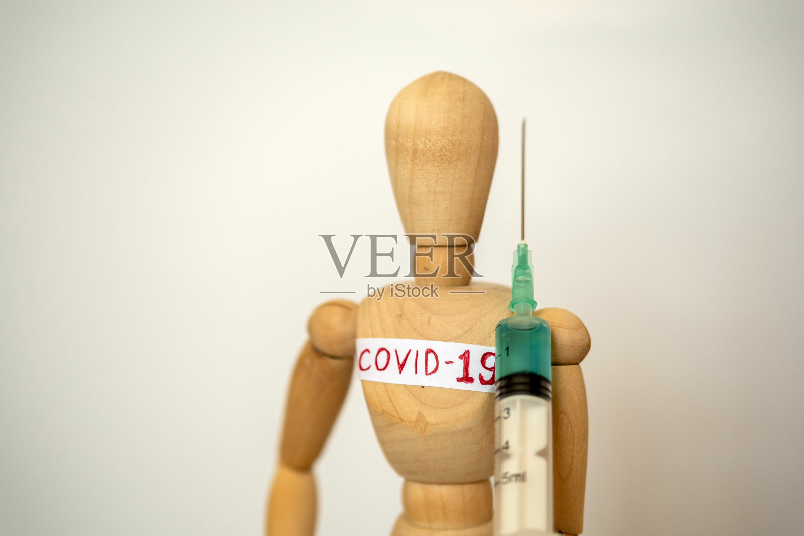 一个木制模型男子的特写带着注射器。照片摄影图片