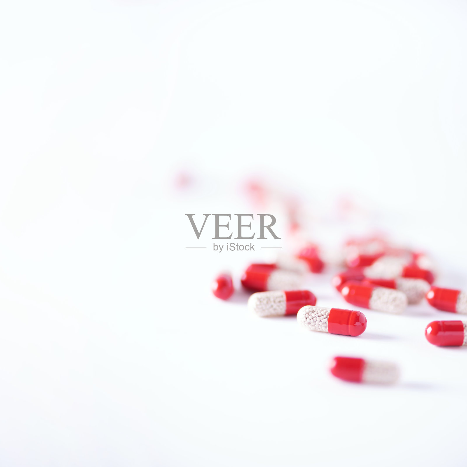 红色胶囊在白色背景下的微距。副本的空间。一堆药治疗感冒冠状病毒Covid-19。照片摄影图片