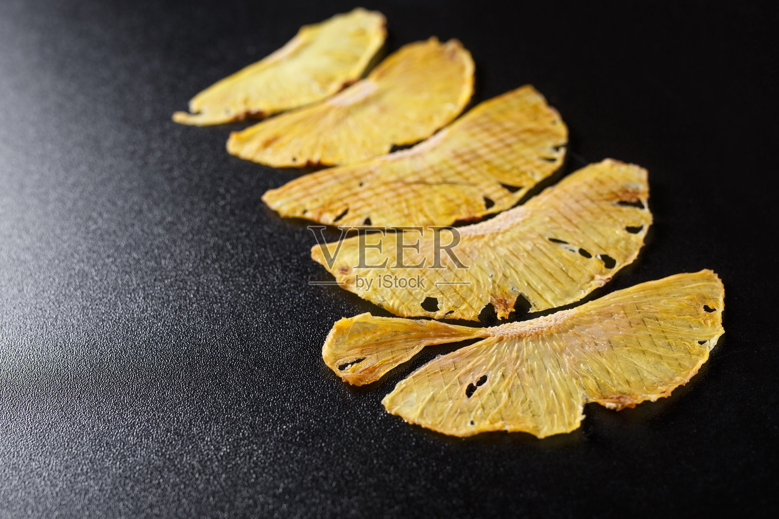 五片干菠萝放在黑色的背景上照片摄影图片