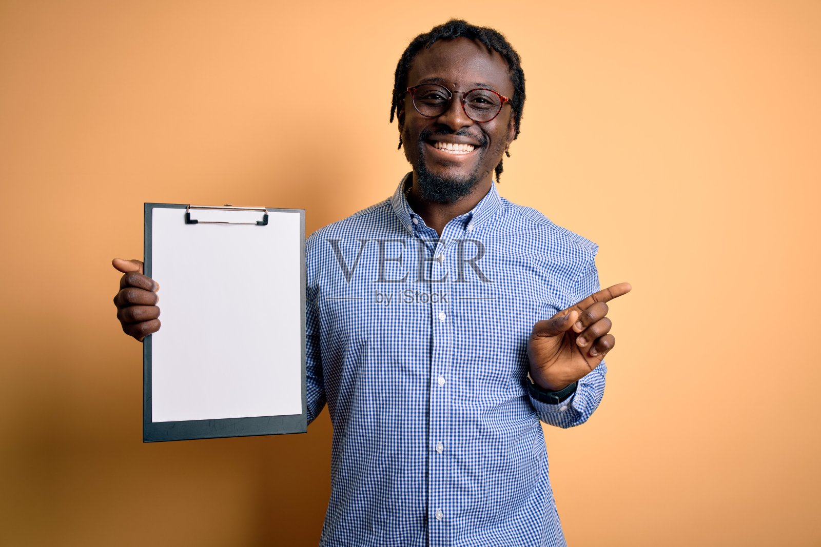 年轻的非洲裔美国检查员戴着眼镜，拿着剪贴板检查表，非常高兴地用手和手指指着一边照片摄影图片