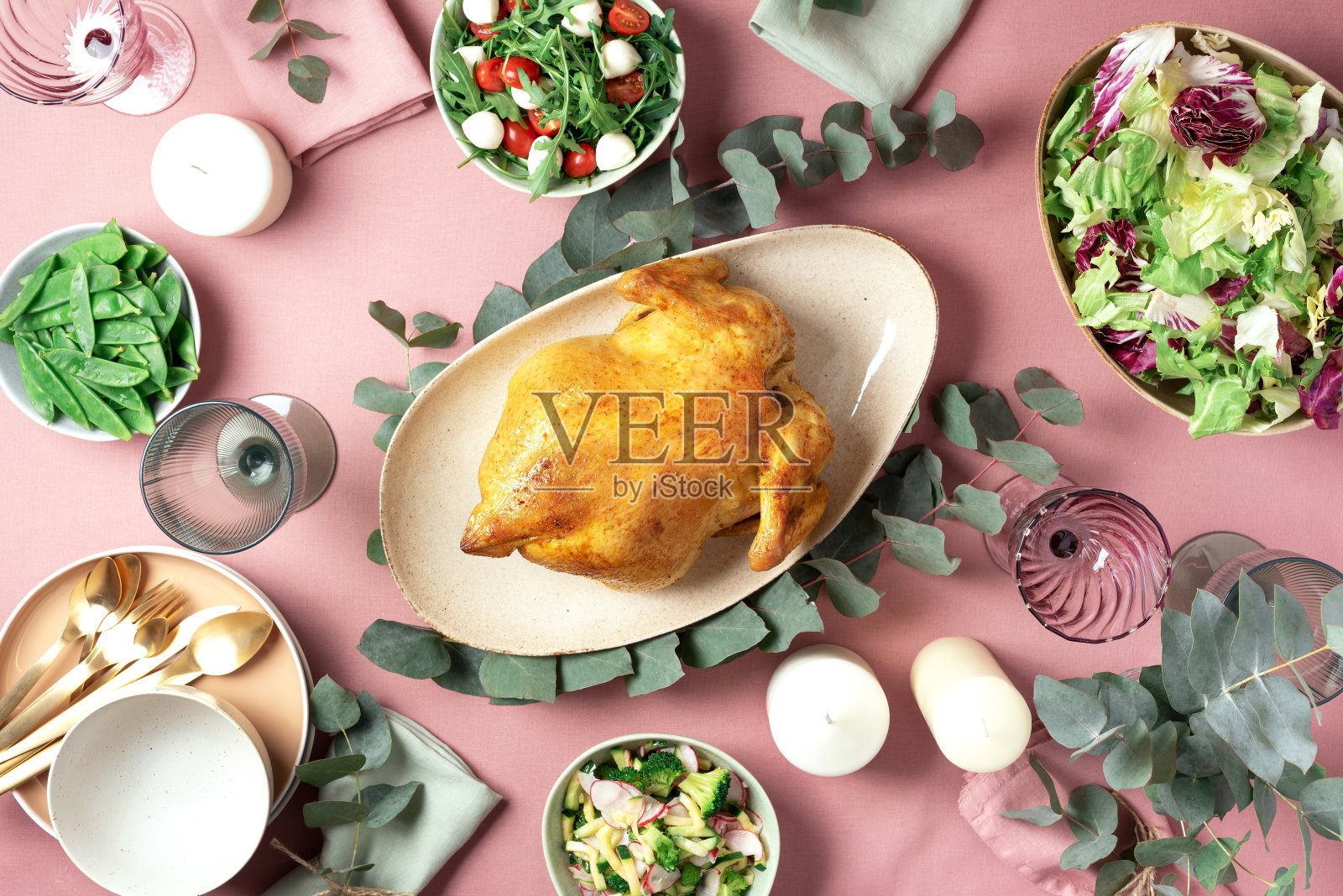 节日家庭餐桌。上菜的盘子，碗与沙拉和蔬菜菜肴，零食，整烤鸡，桉树花在粉红色破旧的背景。情人节，妇女节，母亲节，婚礼早午餐，节日家庭午餐照片摄影图片