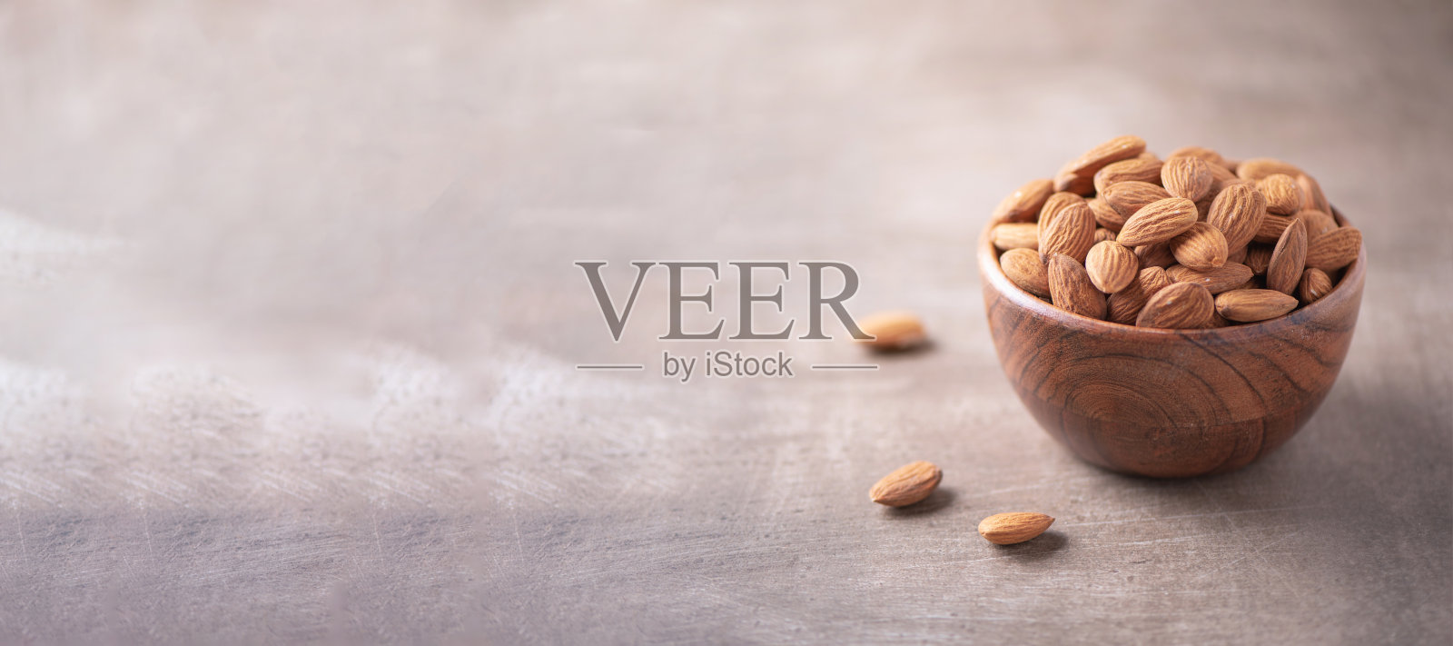 杏仁坚果木碗木纹理背景。副本的空间。超级食物，素食，素食的概念。宏观的杏仁坚果质地，选择性聚焦。健康的零食照片摄影图片