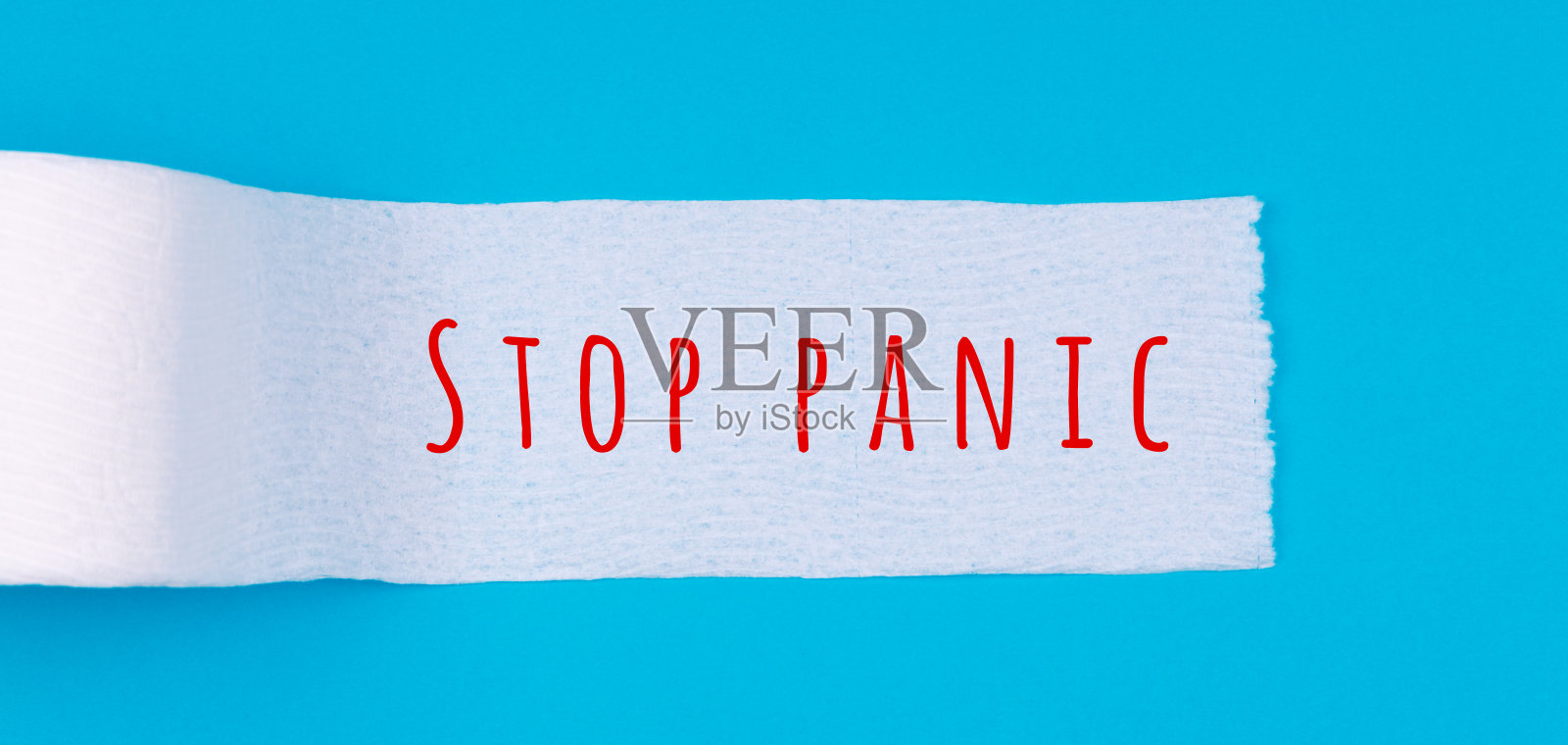 亮蓝色背景上印有“停止恐慌”字样的卫生纸卷。新冠肺炎大流行恐慌购物，社交距离概念照片摄影图片