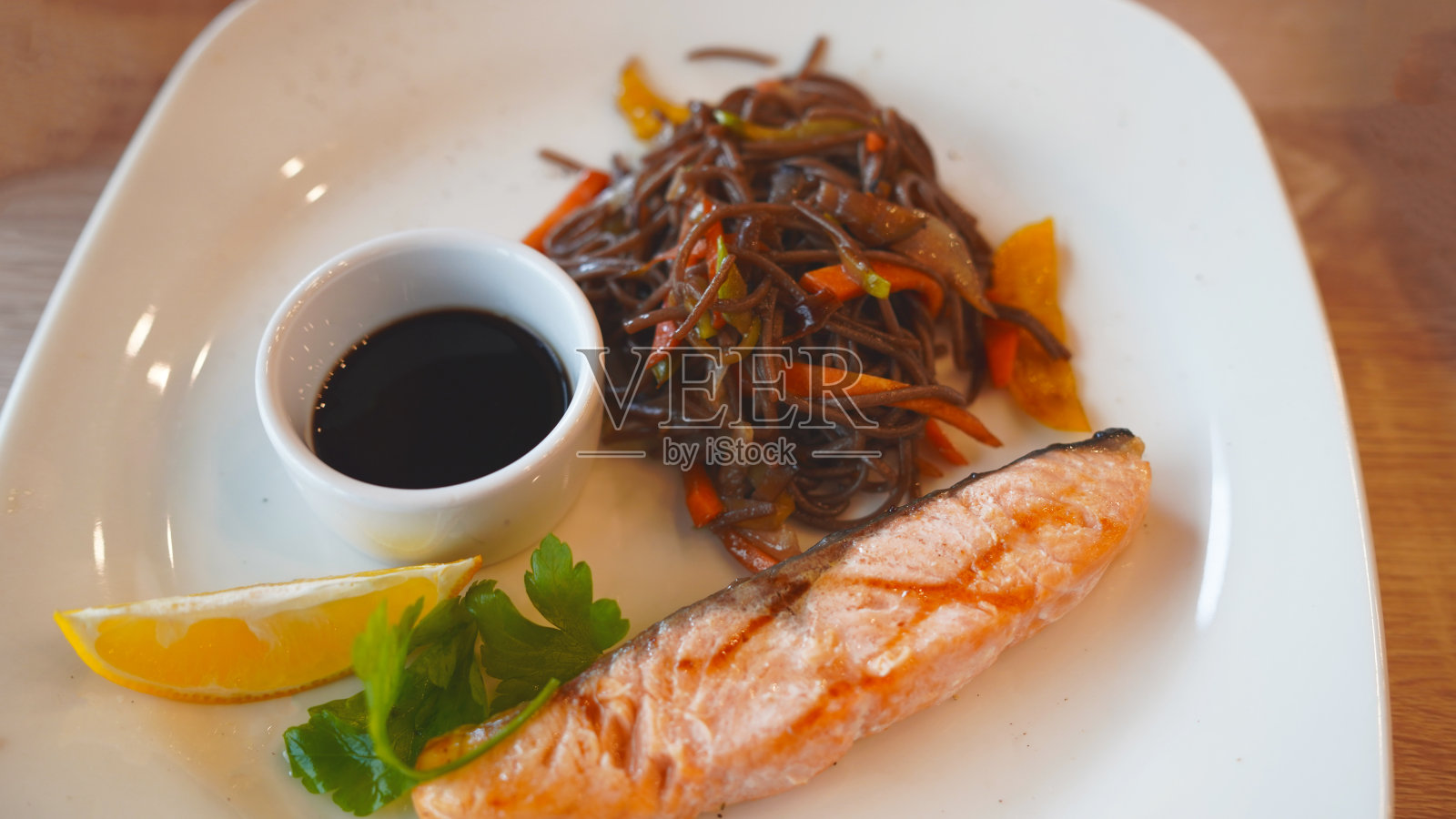 这是一道美味的荞麦面，上面有三文鱼和酱油，还有一片柠檬照片摄影图片