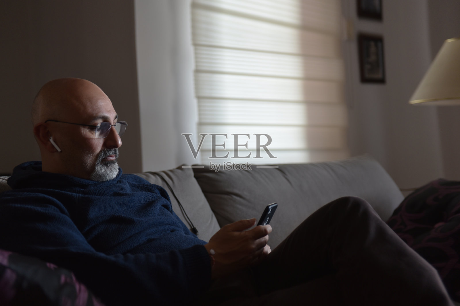 中年男子用蓝牙耳机在手机上听音乐照片摄影图片