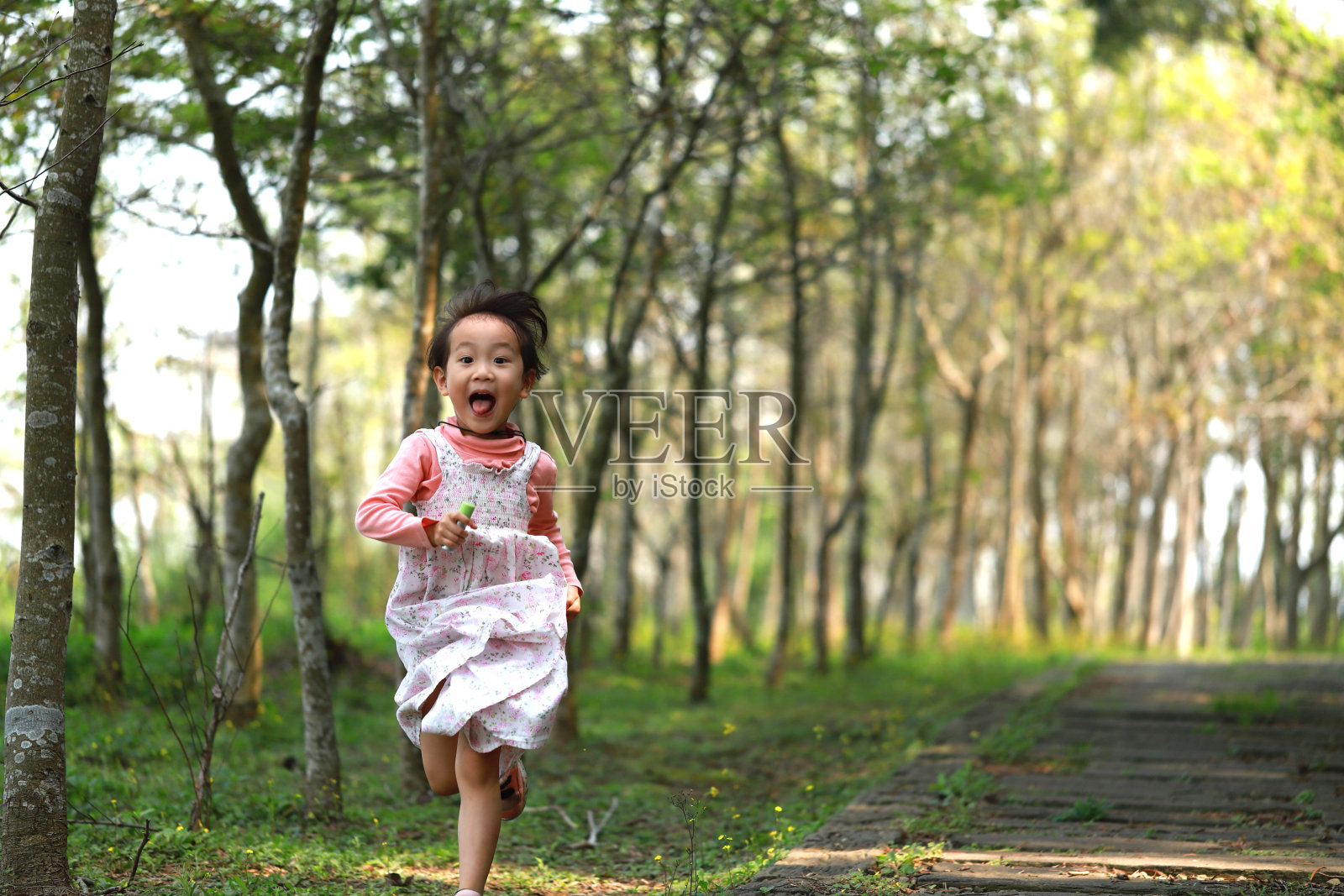 一个在森林里奔跑的亚洲女孩。照片摄影图片