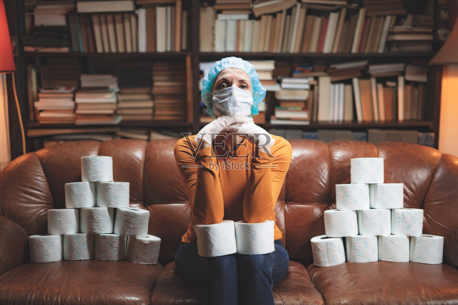 戴防护口罩、储备卫生纸的女人在家隔离中焦虑地等待照片摄影图片