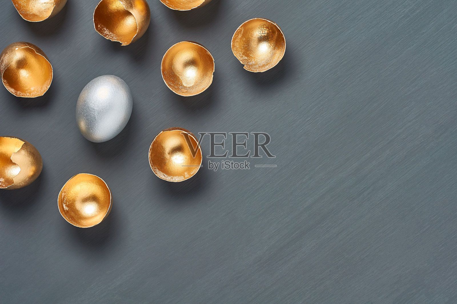 银色的鸡蛋和金色的贝壳在深色的混凝土背景上。复活节的概念，无价的创意，成功的商业投资或奢华的早餐。副本的空间。俯视图照片摄影图片