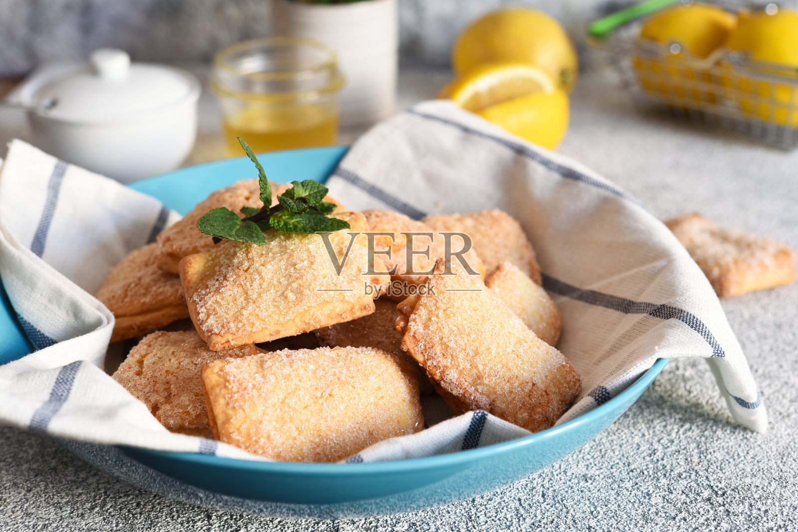 厨房桌上放着柠檬饼干，上面撒着糖和柠檬皮。照片摄影图片