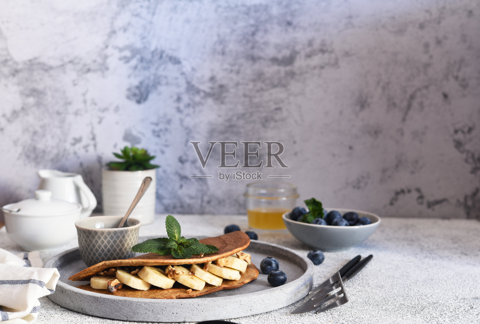 厨房桌上的早餐是薄煎饼、香蕉和蓝莓。照片摄影图片