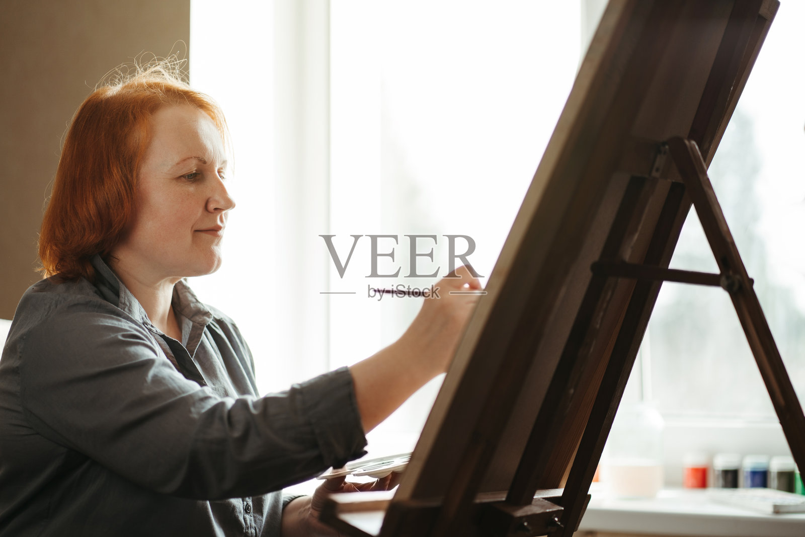 坐在画架旁用水彩画画的女人照片摄影图片