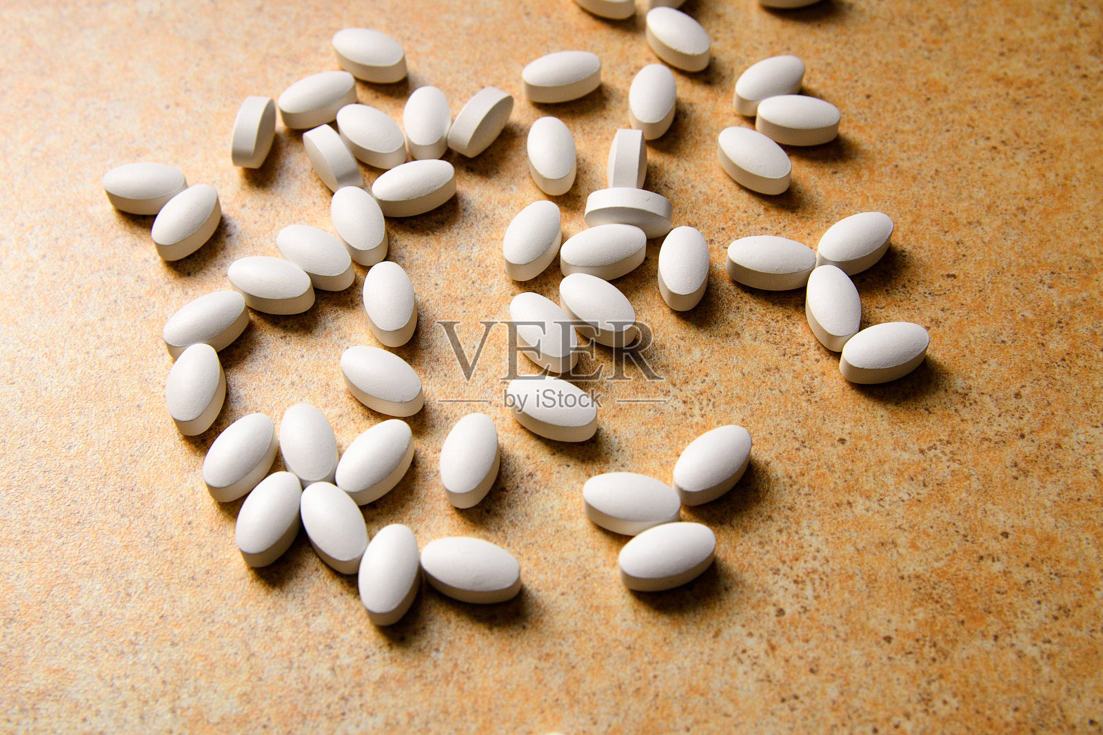 维生素D药片凌乱地躺在沙台面上照片摄影图片