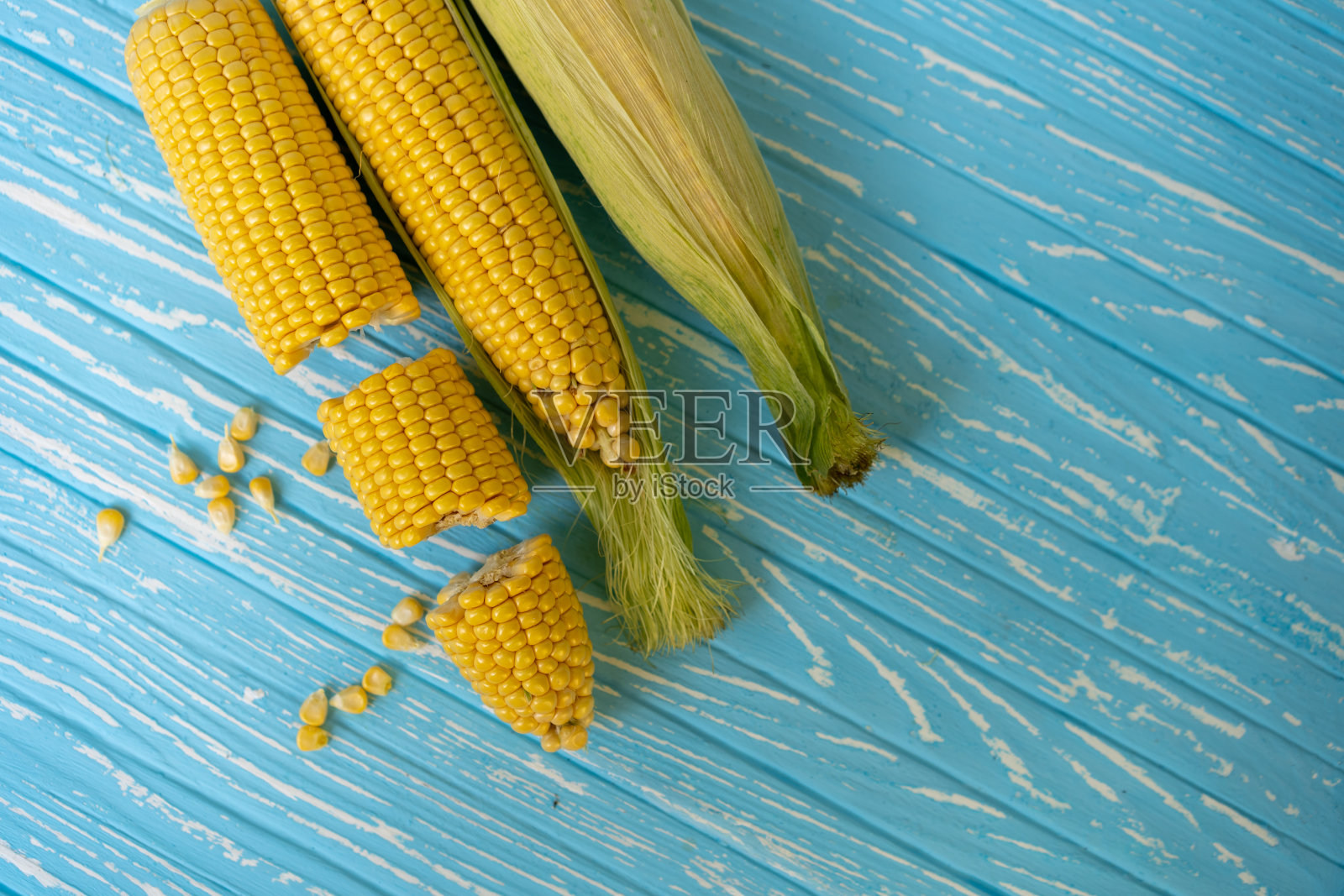 蓝色背景上是绿叶玉米芯。照片摄影图片