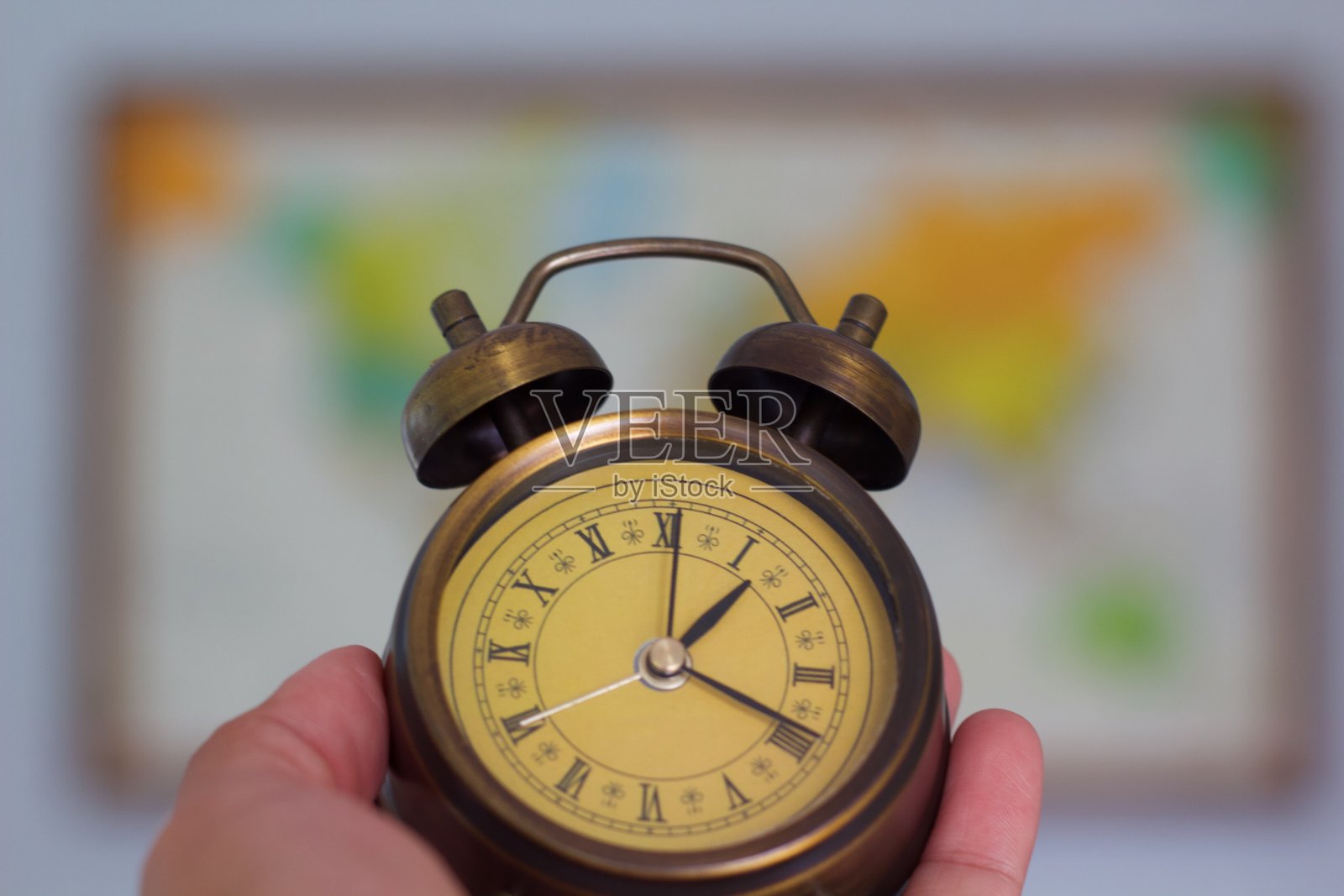 闹钟在手与复古世界地图背景。照片摄影图片