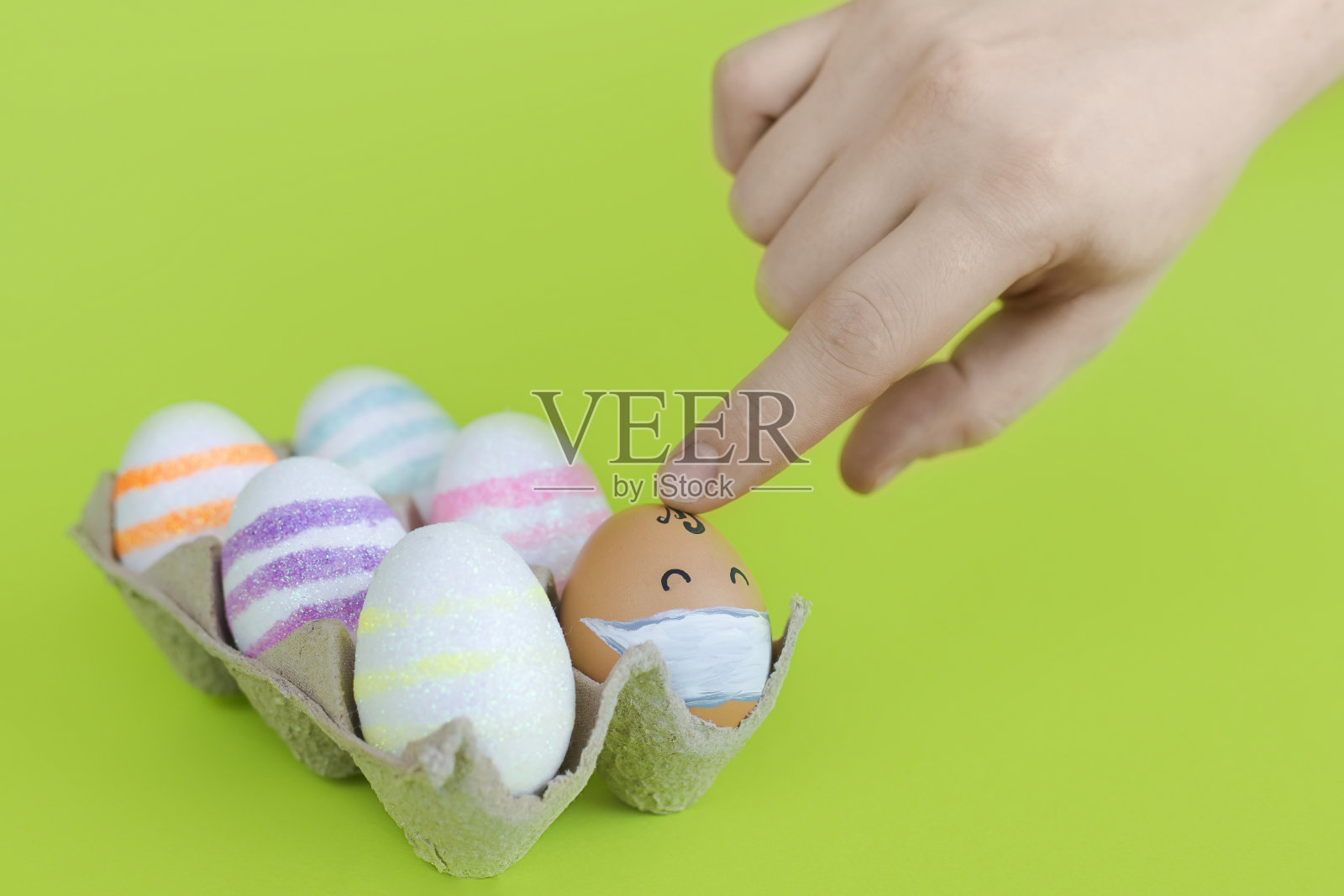 盒子上装饰着闪亮的复活节彩蛋和一个戴着医用口罩的鸡蛋照片摄影图片