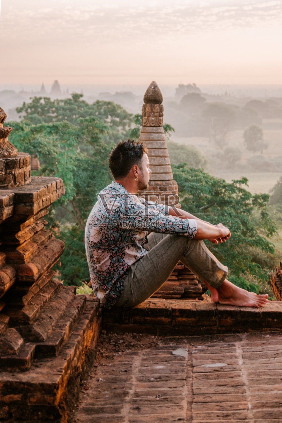 缅甸蒲甘：年轻男子在古庙屋顶观看日出照片摄影图片