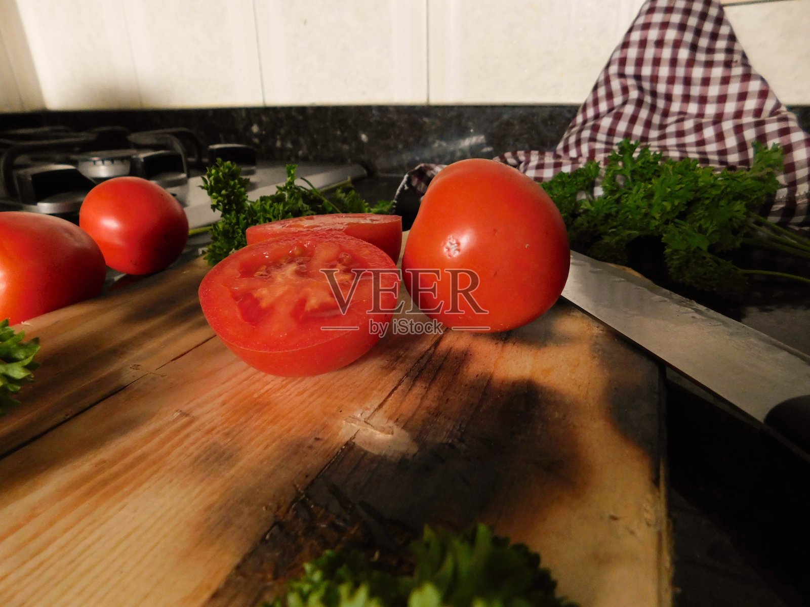 在木板上的新鲜欧芹和大理石背景上的厨房物品，切成一半的西红柿照片摄影图片