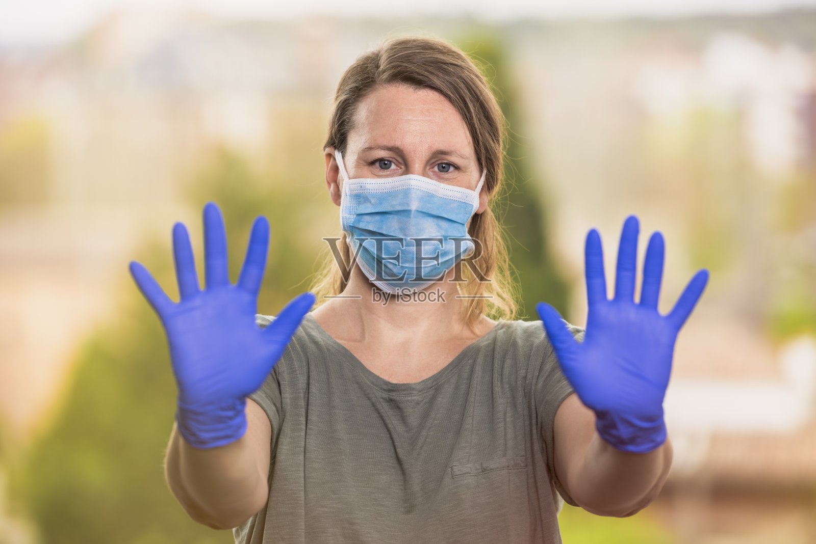 戴口罩的金发女子用手势阻止冠状病毒传播照片摄影图片