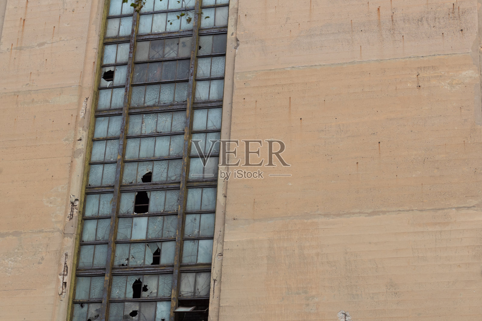 废弃的工业建筑墙壁与破碎的金属框架玻璃窗户，复制空间照片摄影图片