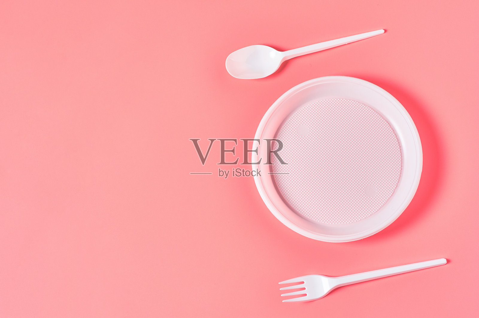 粉红色背景上散落着一次性塑料餐具。节约环境、生态、野餐、聚会等休闲活动的理念。副本的空间。俯视图照片摄影图片