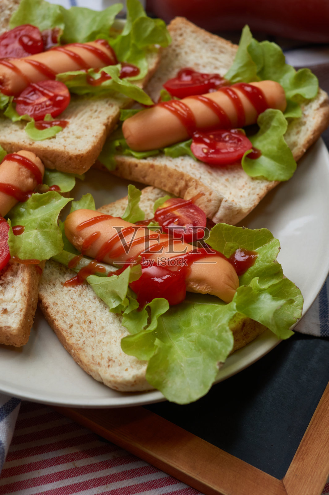 面包上有番茄和绿橡木的热狗照片摄影图片