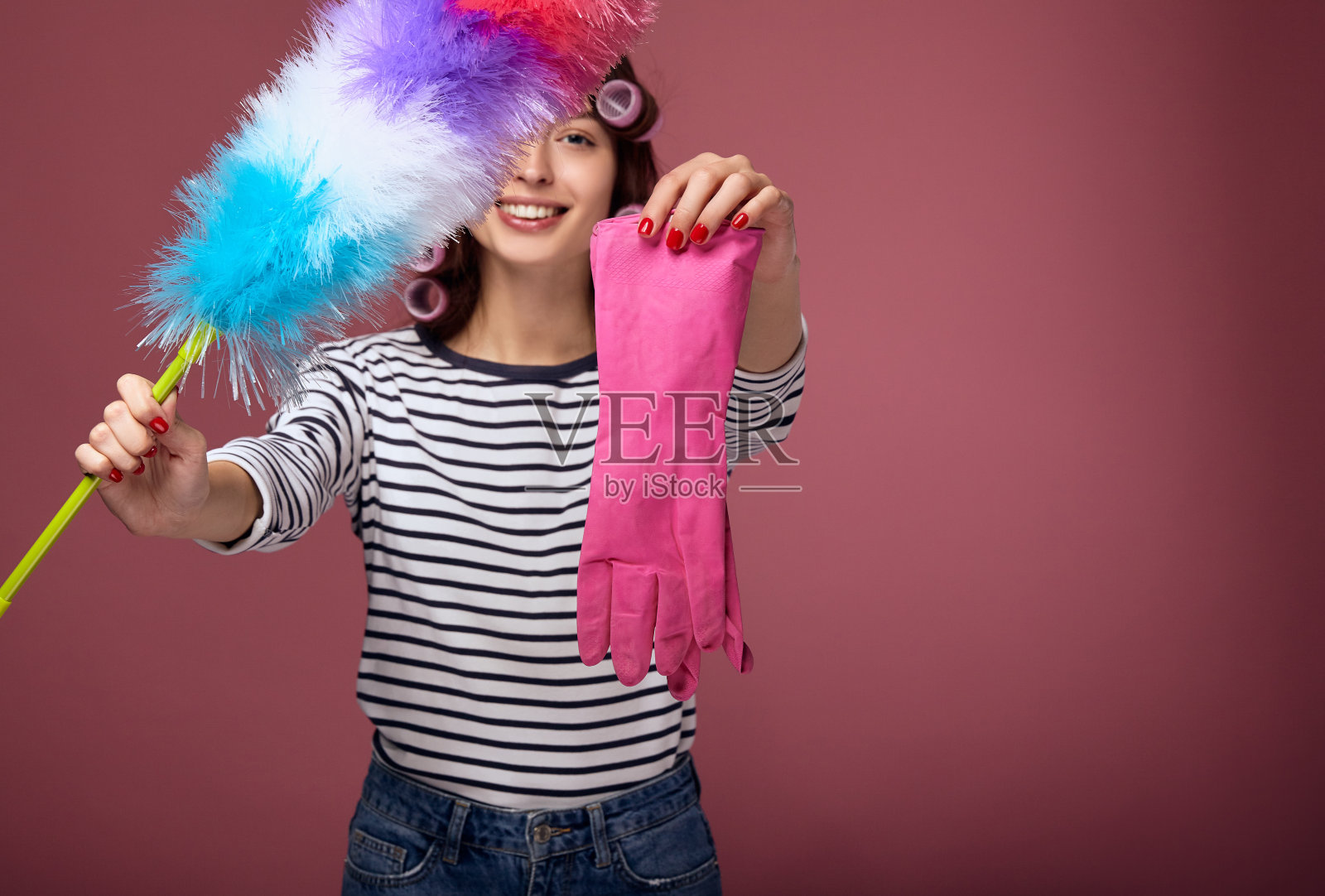 女孩拿着鸡毛掸子和粉色橡胶手套照片摄影图片