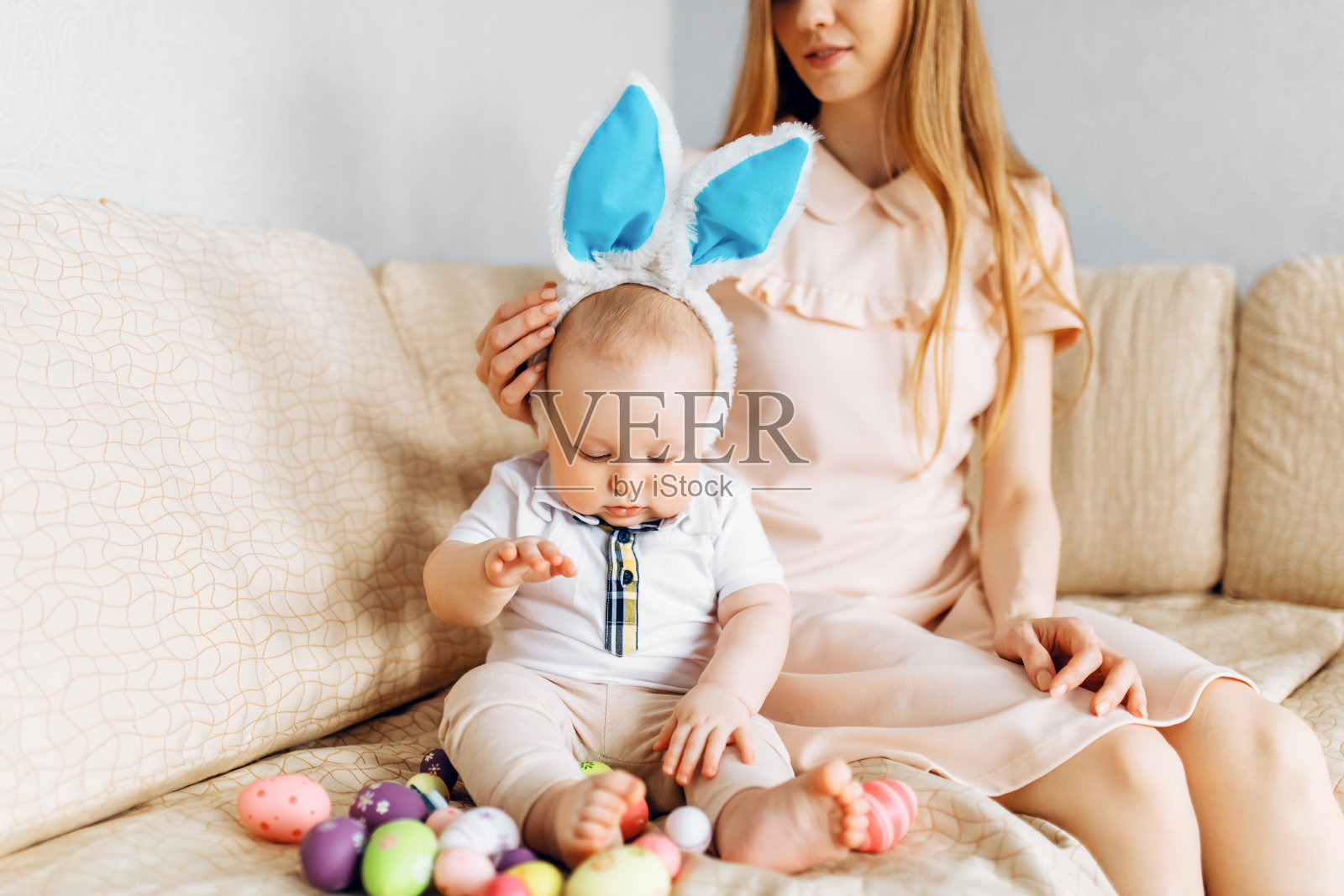 母亲和宝宝戴着兔耳朵，篮子里装着复活节彩蛋，亲子室内玩耍庆祝复活节照片摄影图片