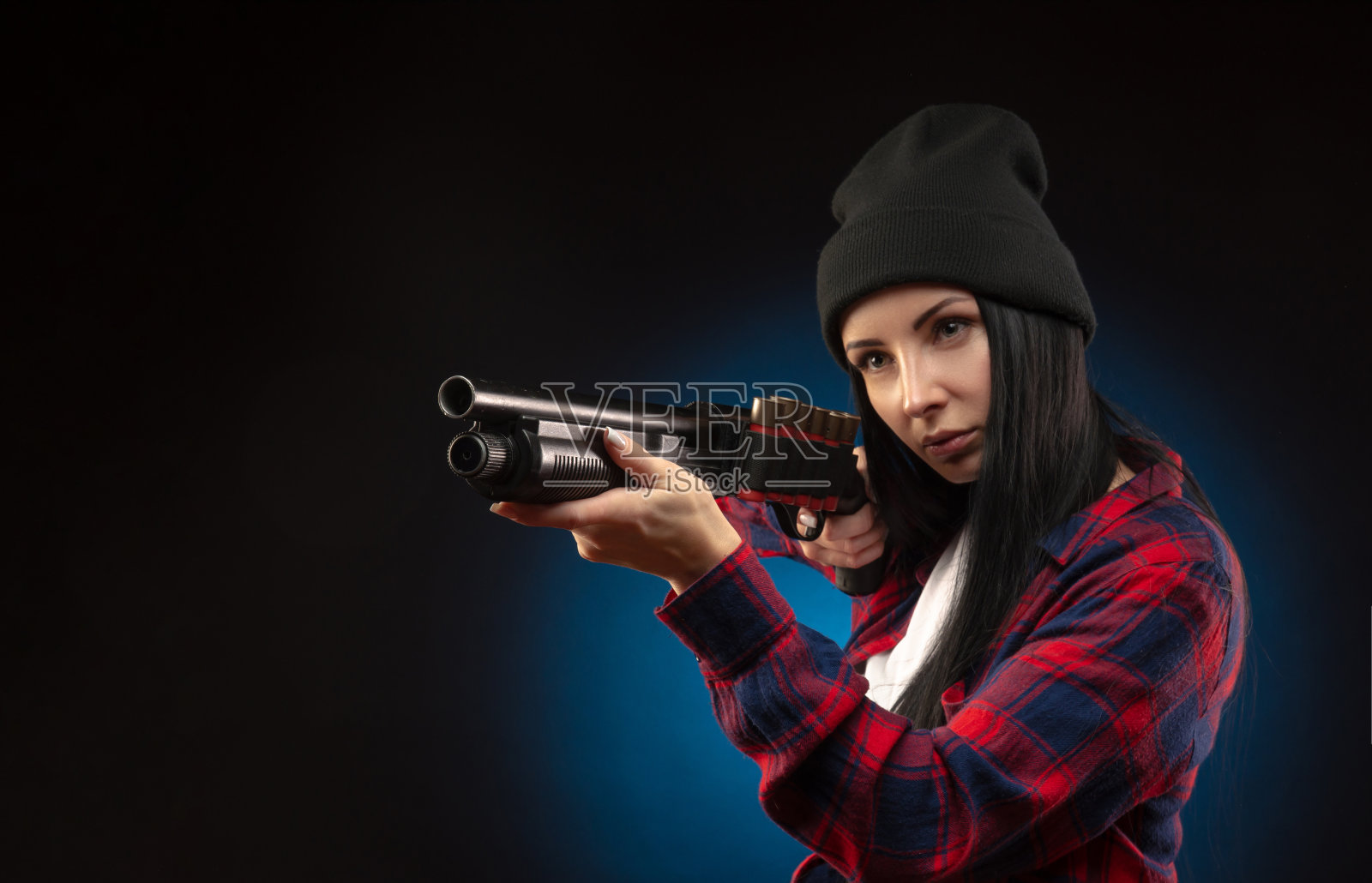 深色背景下手持猎枪，身穿格子衬衫的女孩照片摄影图片